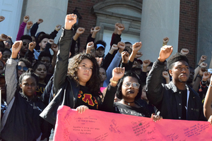Syracuse University community members stand on the steps of Hendricks Chapel with their fists raised in the air to conclude their march against police brutality.