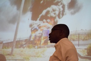 Shawn Ginwright stands in front of a PowerPoint presentation displaying a photo of a playground lit on fire by kids in the San Francisco neighborhood Bayview-Hunters Point. The neighborhood experiences a large amount of violence, the associate professor said during his Thursday presentation in Maxwell Hall.