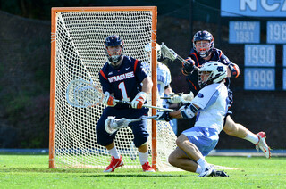 A UNC player gets off a backhanded shot as SU defender Brandon Mullins lunges to block it.