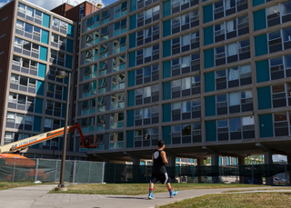 A student passes by DellPlain Hall, where upgrades to the building's dorms will be completed before the fall semester starts. Photo taken Aug. 8, 2017